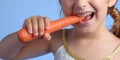 A child with healthy strong white teeth gnaws a carrot. healthy concept