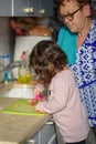 Child help at home.Cooking with kids,healthy food,family love.Toddler girl with grandmother in kitchen peeling carrots.