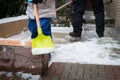 Child helping father clearing snow from sidewalk. Candid authentic family winter activities. Snow shovelling.