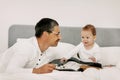 Child in his bed at home plays with dad and touches his guitar Royalty Free Stock Photo