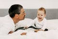 Child in his bed at home plays with dad and touches his guitar Royalty Free Stock Photo