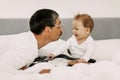 Child in his bed at home plays with dad and touches his guitar Royalty Free Stock Photo