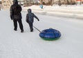 The child and his father are dragging a sledge tubing for skiing down the hill in the city Park in winter Royalty Free Stock Photo