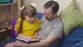 child with his father read an interesting book laugh, kid studies school homework remotely with dad, little girl laughs