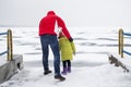 A child with his father walks in dangerous proximity to a frozen lake or river