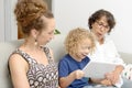 Child and his mother with grandmother play with tablet Royalty Free Stock Photo