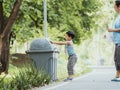 Child and his mother in teaching to drop things on trash in park