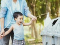 Child and his mother in teaching to drop things on trash in park