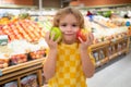 Child hold apple fruits at grocery store. Kid choosing fruits and vegetables during shopping at vegetable supermarket Royalty Free Stock Photo