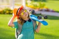 Child hold skateboard on a sunny day in the park. Outdoor portrait of little skateboarder. Child riding skateboard in