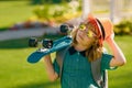 Child hold skateboard on a sunny day in the park. Outdoor portrait of little skateboarder. Child riding skateboard in