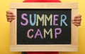 Child holding blackboard with words SUMMER CAMP