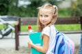 The child is holding a book and a bottle of water. She carries a backpack. The concept of school, study, education, friendship, ch