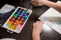 Child holding brush and painting on white paper.Choosing colors for drawing.Watercolor paints and brushes for painting Royalty Free Stock Photo