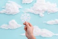 Child holding a cut out showflake on blue sky background