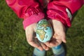 Child holding an egg with Planet Earth painted on it on a sunny day outdoors Royalty Free Stock Photo