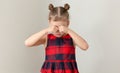 Child holding fists on eyes because of crying offended or scratching because of allergy on grey background