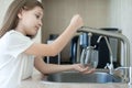 Child is holding a glass under stream of clear transparent cold water from a tap. Close up shot of a young girl pouring a glass of Royalty Free Stock Photo