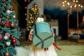 Child holding huge box with gift against backdrop of Christmas decorated at cozy home. Merry Christmas, Happy Holidays. Winter