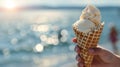 Child holding ice cream cone at the beach, summer delight in hand, blurred ocean backdrop Royalty Free Stock Photo
