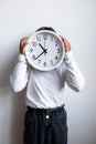 Child holding large clock in front of face against plain background Royalty Free Stock Photo