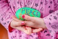 Child holding painted rock with the word Peace.