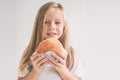 Child holding a piece of hamburger. Kid eats fast food. not helpful food. very hungry baby. Girl isolated on white Royalty Free Stock Photo