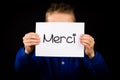 Child holding sign with French word Merci - Thank You Royalty Free Stock Photo