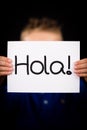 Child holding sign with Spanish word Hola - Hello