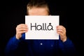Child holding sign with Swedish word Halla - Hello