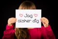 Child holding sign with Swedish words Jag Alsker Dig - I Love Yo