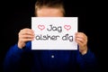 Child holding sign with Swedish words Jag Alsker Dig - I Love Yo