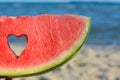 Child holding slice of watermelon with heart shaped hole near sea, closeup Royalty Free Stock Photo