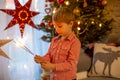 Child holding sparkler at home at New Years Eve, enjoying happy evening