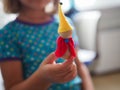 a child is holding a toy wooden gnome.