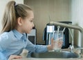 Child is holding a transparent glass. Filling cup beverage. Pouring fresh drink. Consumption of tap water contributes to the