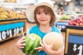 Child holding watermelon in supermarket. Sale, consumerism and kids concept. Vegetables in store. Royalty Free Stock Photo