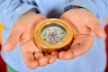 The child holds a compass in his hands and looks at the direction of the arrow
