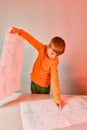 The child holds a drawing in his hand, with the other hand shows a diagram, the concept of teaching children design, engineering,
