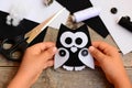 Child holds a felt owl toy in his hand. Small child made an owl out of black and white felt. Teaching children simple sewing