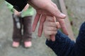 The child holds the finger of the father`s hand against the background of another child`s brother or sister Royalty Free Stock Photo