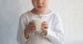 The child holds a glass of milk. Monochrome white background. Faceless face, no face