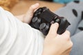 Child holds joystick while sitting on couch at home, playing video game on laptop computer