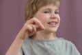 The child holds a lost tooth in his hand. There are traces of caries on the tooth. Removal of a tooth. Loss of a milk