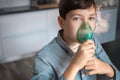 Child holds a mask vapor inhaler. breathing through a steam nebulizer. concept of inhalation therapy apparatus.