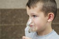 Child holds a mask vapor inhaler. Child who got sick by a chest infection after a cold or the flu that has trouble breathing and