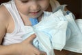 The child holds medical white masks in his hands