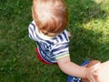 Child holds mom`s hand. view from above. green grass background Royalty Free Stock Photo