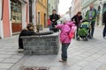 Child holds out hand to living statue artist near Man at Work statue on Panska street