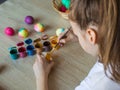 The child holds the painted eggs. A girl in a white T-shirt paints Easter colored eggs with paints and a brush close-up. Spring Royalty Free Stock Photo